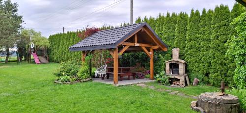 a wooden gazebo with a table and a stove at Pod Jednym Dachem in Skawa