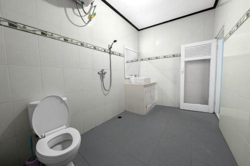 a white bathroom with a toilet and a shower at Dive & Dwell Tulamben in Tulamben