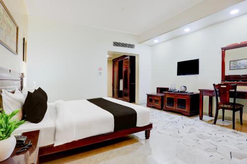 um quarto com uma cama, uma escrivaninha e uma televisão em Palette Hotel And Resort Anand Formerly Hotel La Casa Inn em Anand