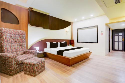 um quarto de hotel com uma cama e uma cadeira em Palette Hotel And Resort Anand Formerly Hotel La Casa Inn em Anand