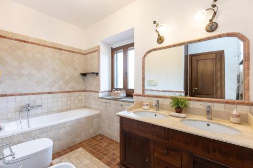 a bathroom with two sinks and a tub and a toilet at Villa Flo' - Piscina Privata, Relax & Privacy in Manciano