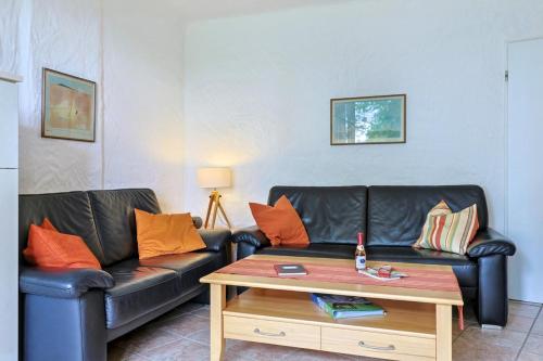 a living room with a black leather couch and a coffee table at Appartment Sünnschien in Kronsgaard
