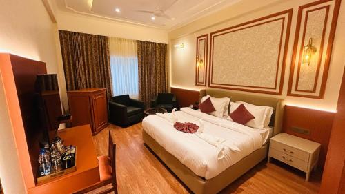 a hotel room with a bed and a desk and a television at Hotel Kamal Palace in Jalandhar