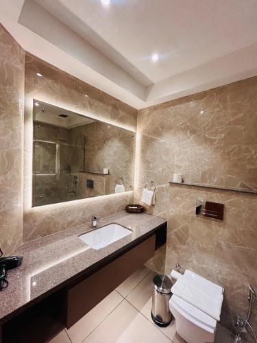 a bathroom with a sink and a mirror and a toilet at Hotel Kamal Palace in Jalandhar