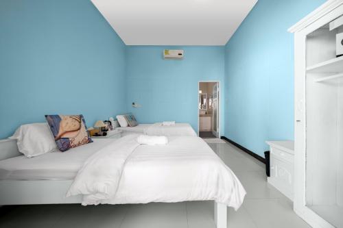 a bedroom with a white bed with a blue wall at Dive & Dwell Tulamben in Tulamben