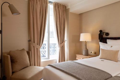 a bedroom with a bed and a chair and a window at Hôtel Aubépine in Paris