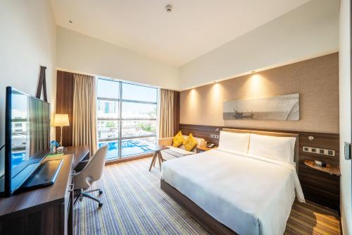 a hotel room with a bed and a desk and a television at Hampton By Hilton Dubai Airport in Dubai