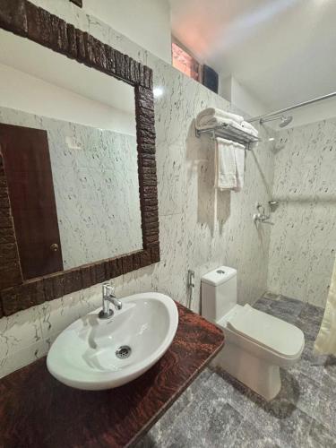 a bathroom with a sink and a toilet and a mirror at Nazri Hotel - Near Arambol Beach in Arambol