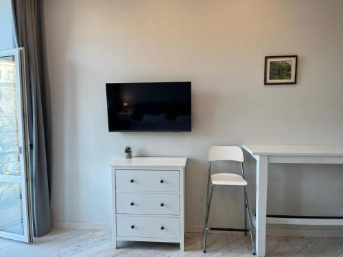 a white desk with a chair and a tv on a wall at Lucky Apartmens in centre Lviv in Lviv