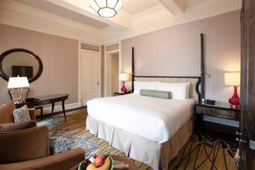 a hotel room with a large bed and a desk at Fairmont Peace Hotel on the Bund in Shanghai