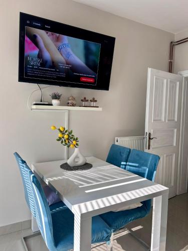 a white dining room table with blue chairs and a tv at Apartment Laura in Senj