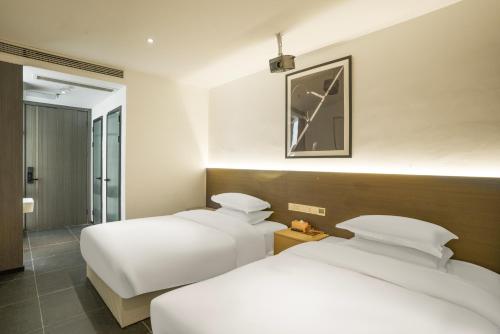 two beds in a hotel room with white sheets at Time Wharf Hotel - Jiefangbei Shibati Branch in Chongqing