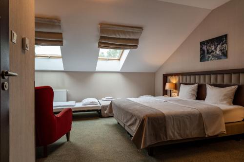 a bedroom with a large bed and a red chair at Grand Sal in Wieliczka