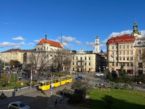 a city with a yellow bus in front of buildings at Lucky Apartmens in centre Lviv in Lviv
