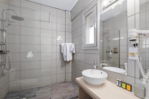 a white bathroom with a sink and a mirror at Pandream Hotel Apartments in Paphos City