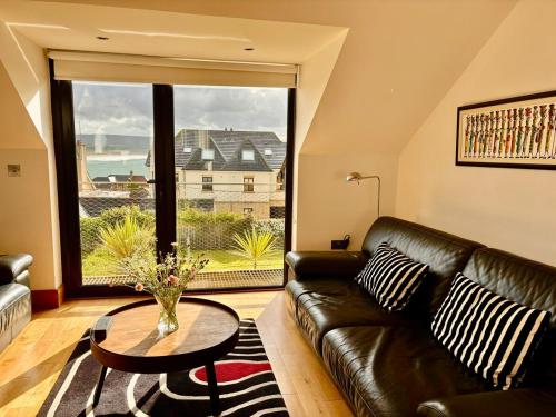 a living room with a leather couch and a table at Luxury Coastal Getaway in Portstewart