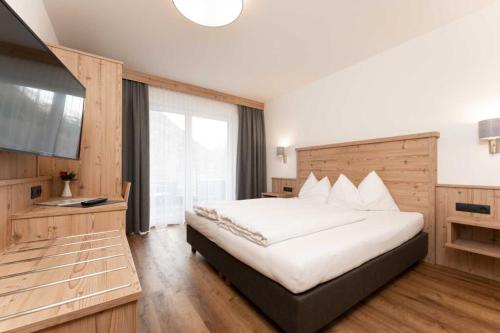 a bedroom with a large bed and a television at Gasthof Brückenwirt Hotel in Sölden