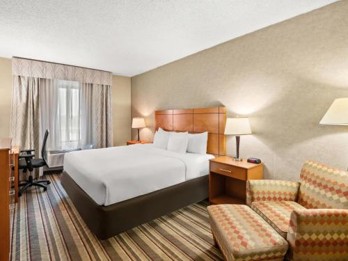 a hotel room with a bed and a chair at Comfort Inn Metro Airport in Romulus