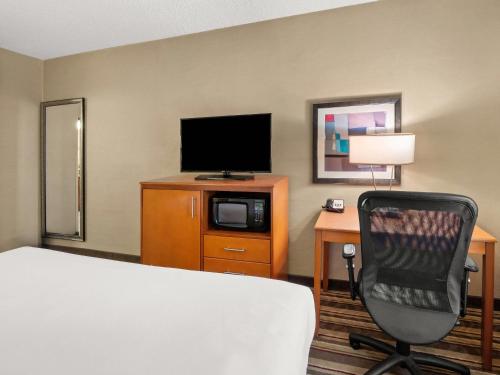 a hotel room with a bed and a television and a chair at Comfort Inn Metro Airport in Romulus