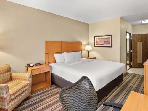 a hotel room with a large bed and a chair at Comfort Inn Metro Airport in Romulus