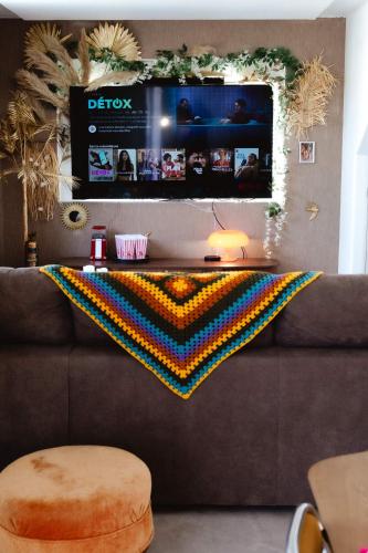 a brown couch with a colorful blanket on it at Maison Castor, balnéo et billard chez Ivona Vacances in Mimizan
