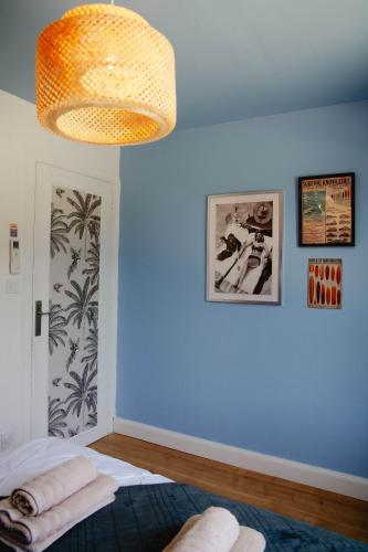 a room with a blue wall with a bed and a chandelier at Maison Castor, balnéo et billard chez Ivona Vacances in Mimizan