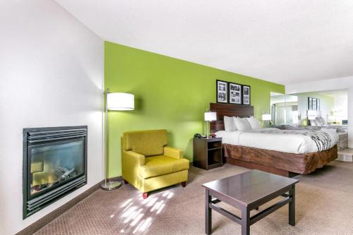 a hotel room with a bed and a chair and a fireplace at Sleep Inn & Suites near Sports World Blvd in Gatlinburg