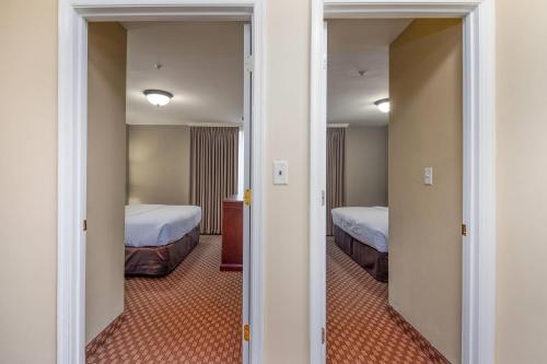 a room with two beds and a hallway with two beds at Clarion Collection Hotel Arlington Court Suites in Arlington