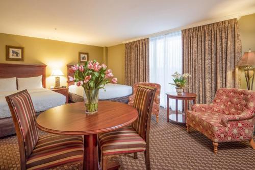 a hotel room with a bed and a table with flowers at Clarion Collection Hotel Arlington Court Suites in Arlington