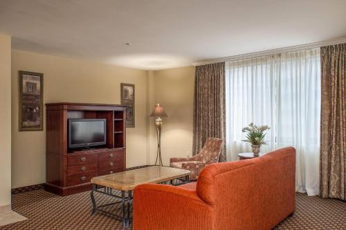 a living room with a television and a couch and a table at Clarion Collection Hotel Arlington Court Suites in Arlington