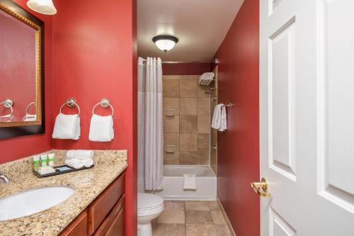 a red bathroom with a sink and a toilet at Clarion Collection Hotel Arlington Court Suites in Arlington