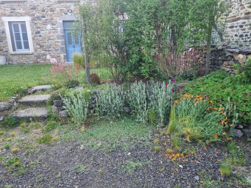 un jardin avec des fleurs et un mur en pierre dans l'établissement Les Chardonnerets - Jardin - Campagne, à Blesle