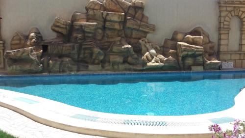 a large swimming pool with a waterfall in the background at Hotel Julius in El Jem