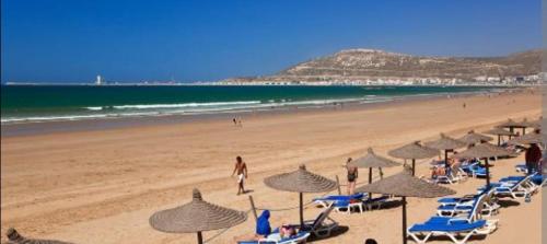 a group of beach chairs and umbrellas on a beach at Riad dar asalam in Agadir