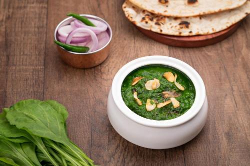 a bowl of green soup with onions and lettuce at Holiday Inn Gurgaon NH8 by IHG in Gurgaon