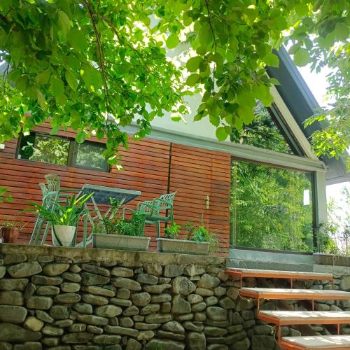 a house with a stone wall and a bench at Woodland Paradise in Gabala