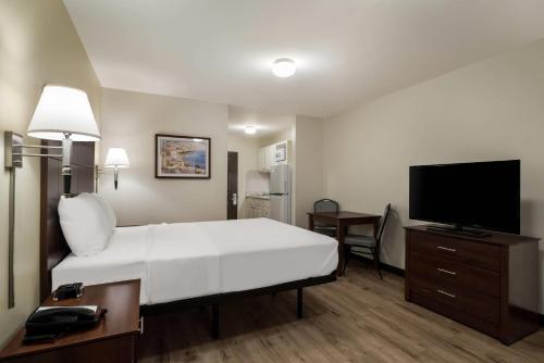 a hotel room with a bed and a flat screen tv at Suburban Studios Denver Central-Arvada in Arvada