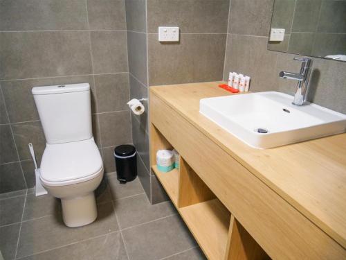 a bathroom with a white toilet and a sink at Nightcap at Hinterland Hotel Nerang in Gold Coast