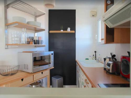 une cuisine avec un micro-ondes et un plan de travail dans l'établissement Appartement T1 bis - LA ROCHELLE - LR130-B56, à La Rochelle
