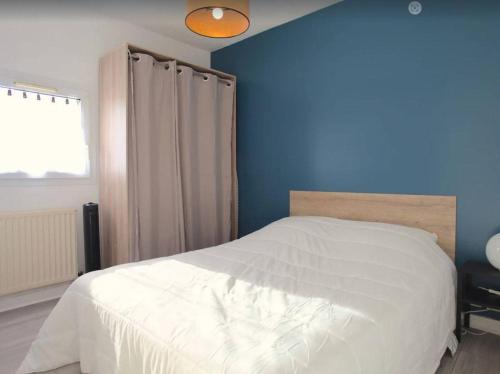 - une chambre avec un lit blanc et un mur bleu dans l'établissement Appartement T1 bis - LA ROCHELLE - LR130-B56, à La Rochelle