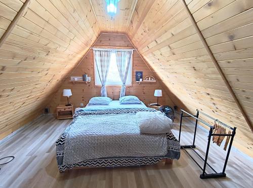 a bedroom with a bed in a wooden attic at Uroczny domek z dużym ogrodem i tarasem blisko jeziora, cisza i spokój in Omin