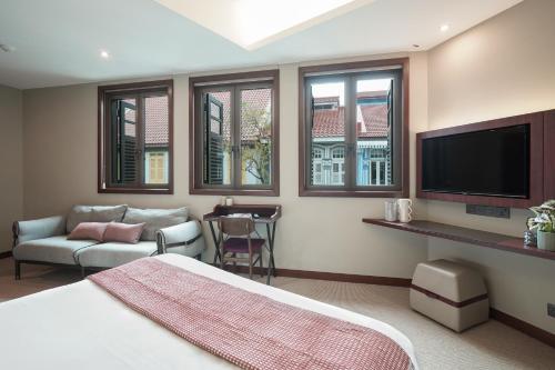 a bedroom with a bed and a tv and a couch at STORIES Joo Chiat, a Hotel by Cove - Paya Lebar, Singapore - NEWLY RENOVATED in Singapore