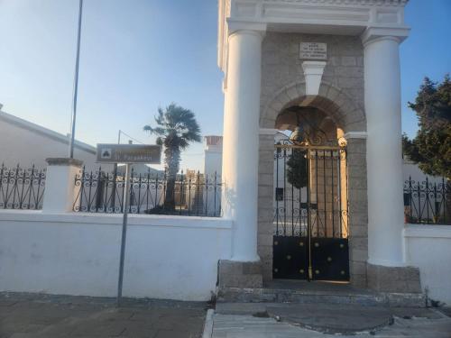a white building with a gate and a palm tree at Laertis Studio in Kattavía