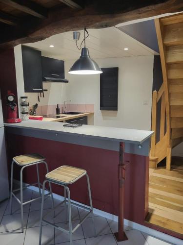 une cuisine avec deux tabourets et un comptoir dans l'établissement Appartement rénové à la campagne, à La Celle-sous-Gouzon