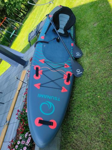 a blue kayak sitting on the grass with a paddle at Przystań Nad Miążką in Sapowice