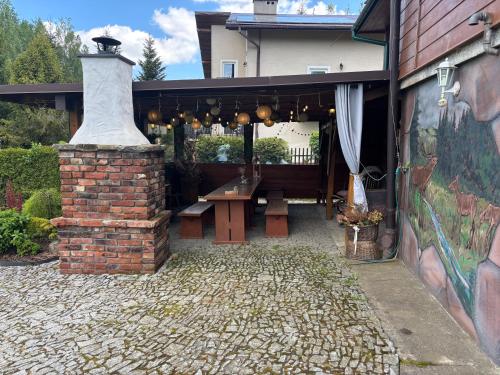 a patio with a picnic table and a brick fireplace at Chata Baśka in Baligród