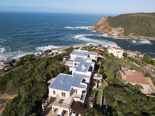 an aerial view of a house on a hill next to the ocean at Castle On The Heads in Knysna