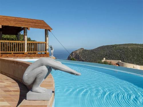 a statue in the water next to a swimming pool at Castle On The Heads in Knysna