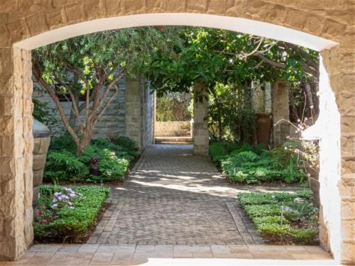 an archway leading into a garden with a pathway at Castle On The Heads in Knysna