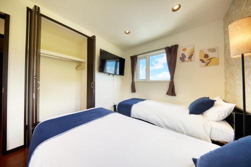 two beds in a hotel room with a window at CODE ROOMS OKINAWA 今帰仁の貸切宿 BBQと自然を満喫 美ら海水族館 ジャングリア沖縄まで車で20分 最大7名ok in Nakijin